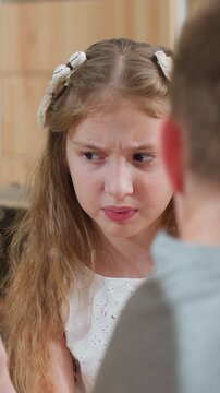 young white girl frowning during scolding, kitchen closeup showing preteen daughter reacting to parent reprimand, hands fiddling with string lights, tense atmosphere and raw emotion across frames,