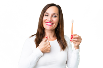 Middle age woman brushing teeth over isolated chroma key background with thumbs up because something good has happened