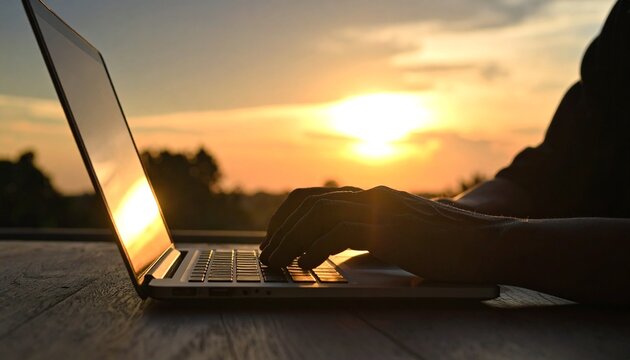 Silhouette of hands typing on a laptop keyboard outdoors at sunset, symbolizing remote work and digital freedom. - Powered by Adobe