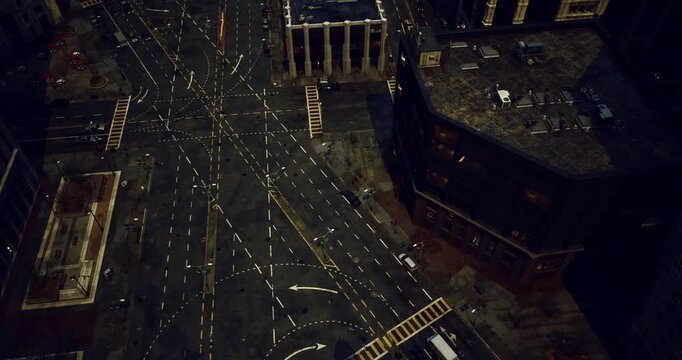 Nighttime view of a busy urban intersection showcasing numerous traffic signals, marked lanes, and occasional vehicles navigating the complex road patterns in a city environment.