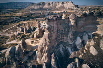 Sweeping aerial shot showcasing towering rock pillars and rugged geological structures set within vast arid volcanic landscape. Autumn in Cappadocia, Nevsehir province, Turkiye