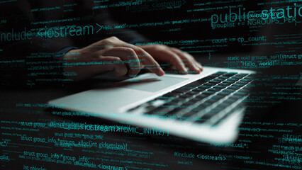 A close-up image showing hands typing on a laptop keyboard with floating lines of code around, illustrating the dynamic world of software development and technology. Xenic