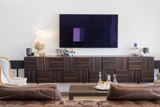 Modern living room with mounted TV, artistic decor, and dark wood floating media console