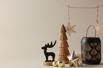 Obraz premium Christmas still life with black lantern, reindeer and wooden tree on beige background. Nordic style home decor for winter holidays.