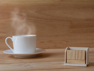 Background of empty wooden calendar blocks with white coffee cup and soft stream smoke on pinewoods floor and blurred brown wooden wall for copy space.