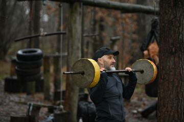 Man lifts weights outdoors in a training session at a park during a rainy day