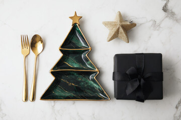A festive holiday table setting featuring a ceramic Christmas tree plate with ribbon and pine sprig, surrounded by gifts