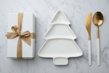 A festive holiday table setting featuring a ceramic Christmas tree plate with ribbon and pine sprig, surrounded by gifts