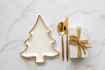 A festive holiday table setting featuring a ceramic Christmas tree plate with ribbon and pine sprig, surrounded by gifts