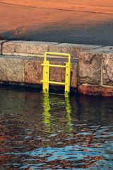 Yellow ladder leading into water at the seafront.