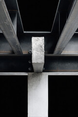 Interior metal structure with cross-shaped black steel beams and mesh panels illuminated by spotlights