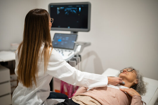 Doctor performing ultrasound examination on woman's neck - Powered by Adobe