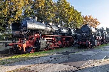 Two massive black steam locomotives, class 52, parked side by side on the tracks at the Veluwsche Stoomtrein Maatschappij during autumn.