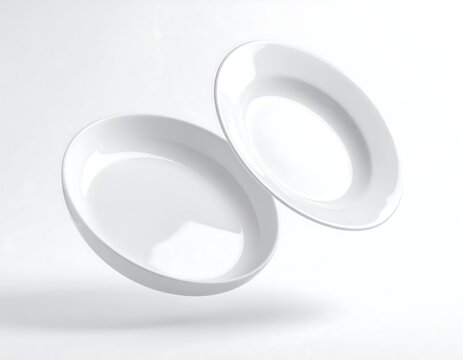 Two clean, glossy white ceramic plates, one tilted, appear to float in a soft, white studio setup
