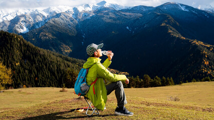 Asain hiker drinking water while resting in the mountains
