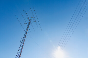 青空を背景にした送電線と通信アンテナ（無線塔）