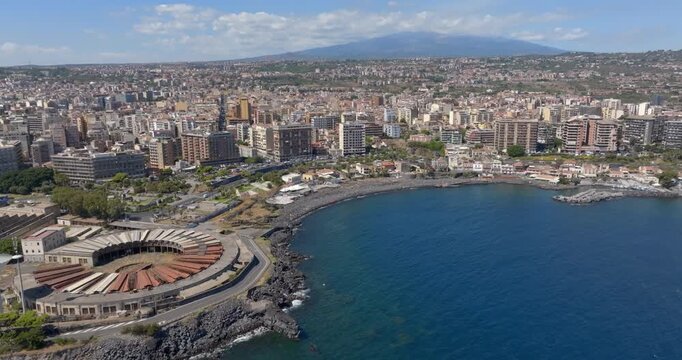 Aerial view of San Giovanni li Cuti beach. It is a small seaside village in the eastern part of the city of Catania, Sicily, Italy. In the background, on the horizon, is Mount Etna in silhouette.