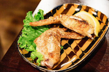 香ばしく焼き上げられた手羽先（鶏肉）とレモンのクローズアップ