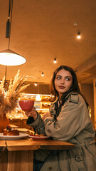 Young woman enjoying a coffee and pastry at a cozy cafe with warm lighting
