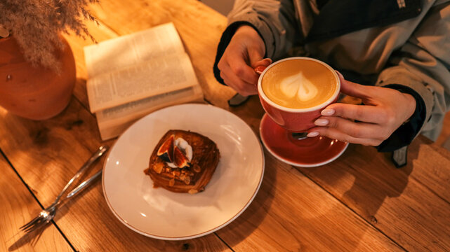 Cozy morning with coffee, pastry, and a book on a wooden table