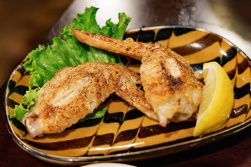 香ばしく焼き上げられた手羽先（鶏肉）とレモンのクローズアップ