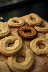 Freshly baked traditional Scandinavian Danish Christmas cookies called Vanilla rings, laying on wooden surface. One over baked black cookies sticks out, diversity and exclusion concept.