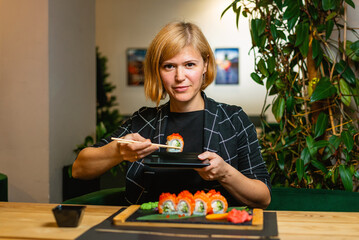 Woman Holding Sushi Roll in Modern Dining Space
