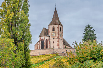 Medieval simultaneum church Saint-Jacques-le-Majeur overlooking the village of Hunawihr and a  vibrant autumn vineyard. 