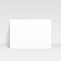 An A4 sheet of paper stands against the wall on a gray background. A mock-up of a letter, leaflet, brochure booklet, flyer, or invitation card. 