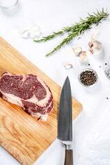 Raw ribeye beef steak with herbs and knife