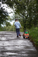 Child playing outdoors pulling toy truck on road