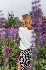Woman surrounded by purple flowers in natural landscape