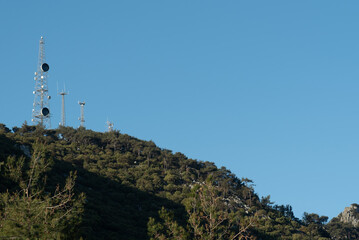 Fototapeta premium Communication towers stand tall on the mountain under a clear blue sky in daylight hours