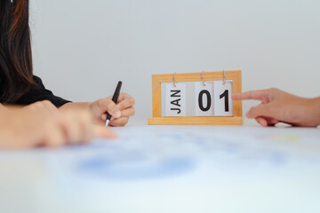 Business meeting with wooden desk calendar showing January 1, new year planning concept, fresh start, goal setting, strategy discussion and corporate future planning.