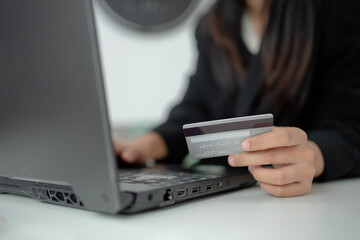 Close up of businesswoman holding credit card while shopping online on laptop, secure payment, ecommerce transaction, digital banking and online finance concept.