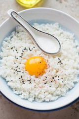 Japanese tamago kake gohan or rice mixed with a raw chicken egg in a white and blue plate, vertical shot, close-up