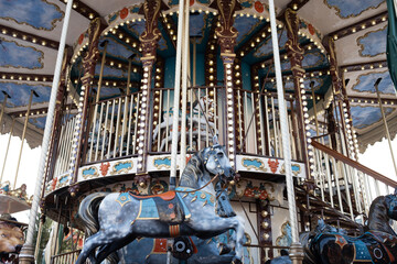 A grand, vintage double-decker merry-go-round with painted horses. Illuminated by warm lights, this classic fairground attraction evokes childhood magic and nostalgia.