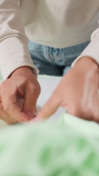 Hands pin fabric, Seamstress prepares fabric pieces, Craftsman carefully pins fabric for garment assembly, Focused seamstress secures fabric pieces with pins before sewing project begins