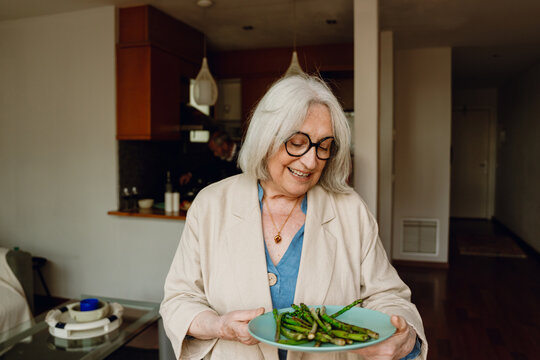 Woman carrying a plate of asparagus and smiling