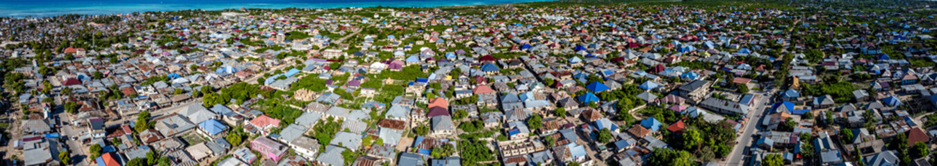 wide angle aerial view across Nungwi,  a village  located in the far northern end of island of Zanzibar, with buildings, houses, infrastructure and turquoise Indian Ocean in the background