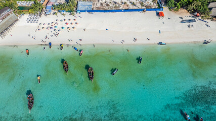 aerial view of Nungwi Beach coastline with sandy beach, turquoise blue water, and parasols, people walking on the beach and boats floating in the water