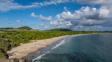 aerial landscape view of Grande Terre Beach in the commune of Sainte-Anne, Martinique, Lesser Antilles, Caribbean, with sandy beach, forest and mountains in background
