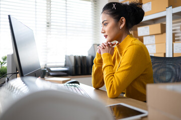Female warehouse staff focused on computer screen, managing online orders