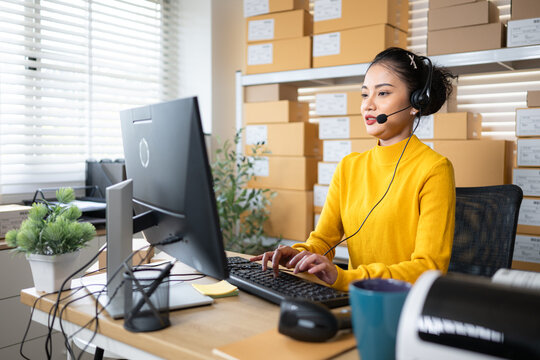 Customer service representative wearing headset working at computer in warehouse office - Powered by Adobe