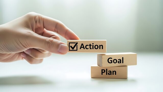 A hand placing a wooden block with action on top of goal and plan blocks