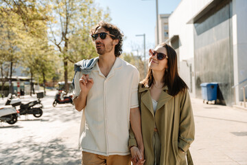Fototapeta premium A man and woman hold hands and look away while she smiles and he talks