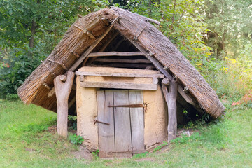 Ancient countryside basement made of clay and wood. Sunny day. Aged wooden peasant house. Retro roof.