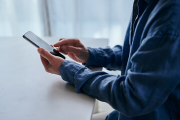 部屋でスマホを操作するシニア女性