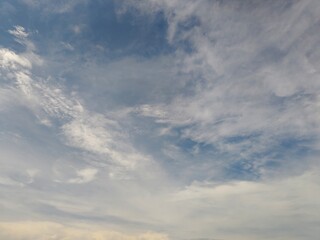 Fototapeta premium Blue sky background with white cirrus and cumulus clouds. Beautiful daytime atmospheric view with soft sunlight. Nature and weather concept.
