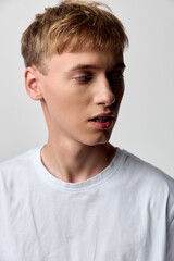Naklejka premium Man in a white t-shirt, studio lighting highlights a thoughtful side view profile, casual style and calm mood. Ideal for fashion, lifestyle, and editorial projects with a clean, modern feel